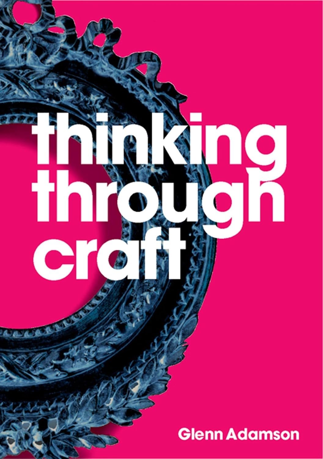 Cover of the product "Thinking Through Craft" by Glenn Adamson, featuring bold white text on a bright pink background with a black ornate circular frame at the top, exploring concepts in contemporary art and.