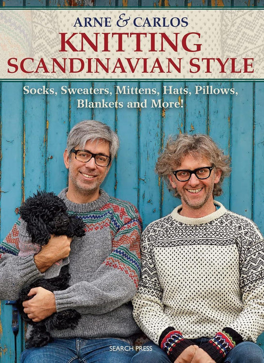 Two smiling men, one holding a black dog, wearing Scandinavian sweaters, pose in front of a blue wooden background. Text above reads "Arne & Carlos Knitting Scandinavian Style" with authors' names "Arne Nerjordet (2014-10-15)" by Search Press.