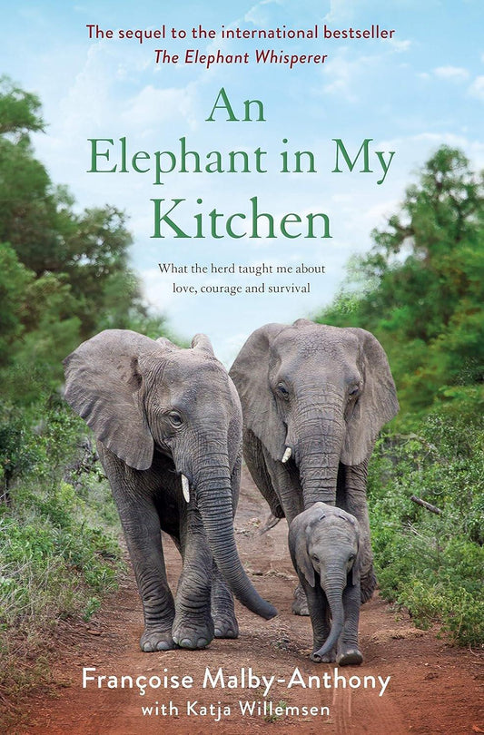 Book cover for "An Elephant in My Kitchen: What the Herd Taught Me About Love, Courage and Survival (Elephant Whisperer, 2)" by Françoise Malby-Anthony and Katja Willemsen, showing two elephants walking on a dirt track in a South African game reserve with lush greenery and trees.